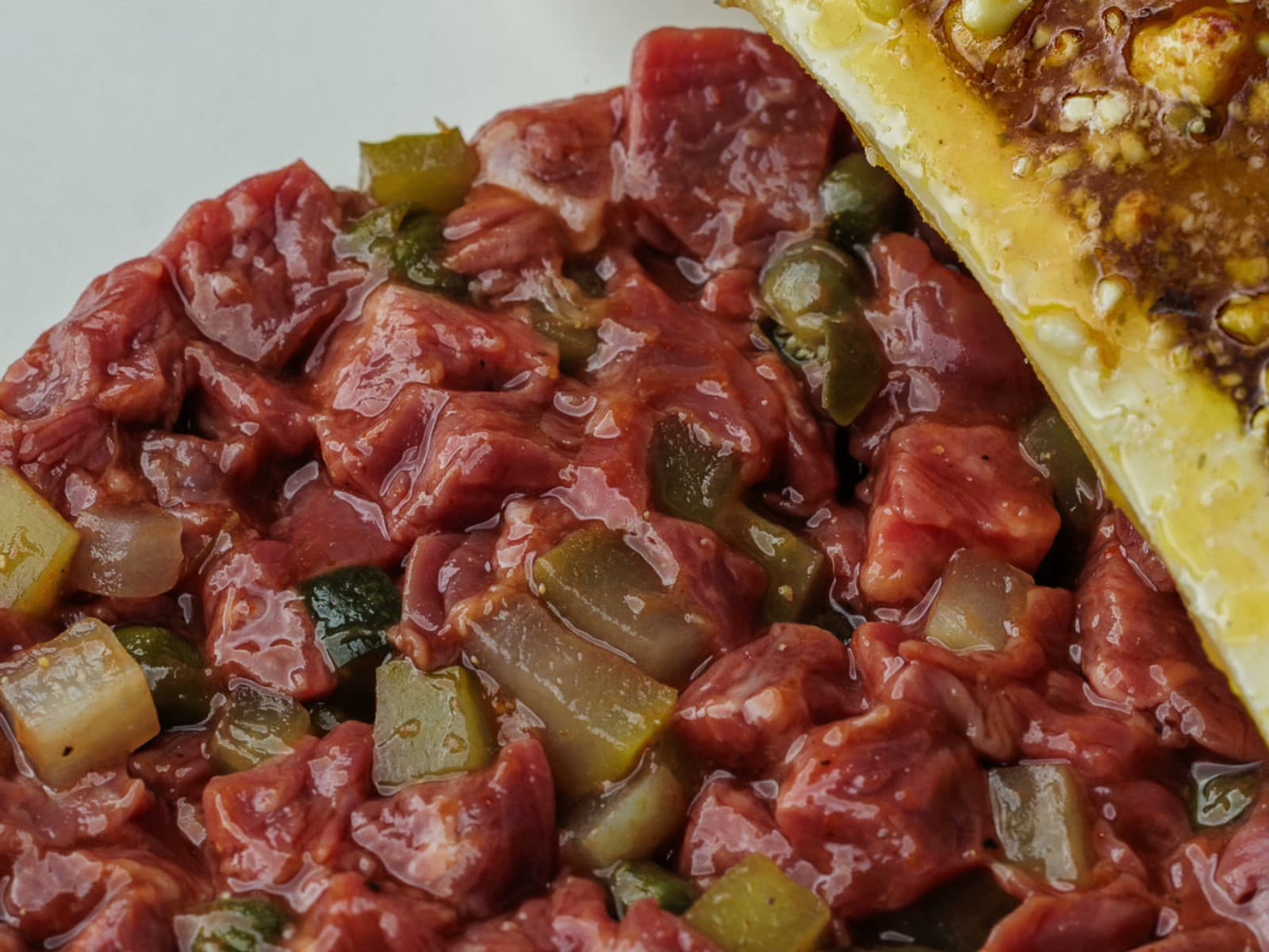 Hand-cut beef tartare from the barrel fillet at Eleven Fifty Five, flecked with diced pickles and capers, a slab of caramelised bone marrow alongside
